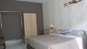 Une chambre à coucher comprenant un lit, une table de chevet, une armoire en bois et une chaise.