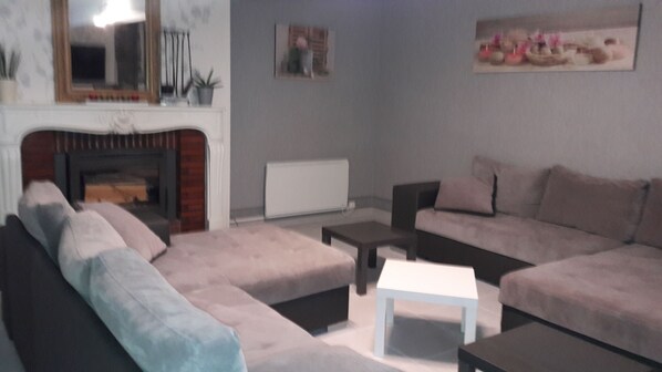 A living room with a fireplace, a sofa set, a coffee table, and a painting on the wall. - cottage, farmhouse. (Bernouil)