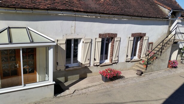Un bâtiment à la façade blanche, doté d’un toit en pente et d’une série de fenêtres équipées de volets.