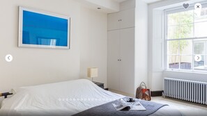 Une chambre à coucher avec un lit, une fenêtre, une armoire et un tableau au mur.