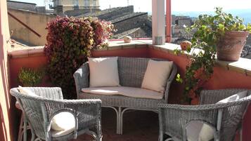 A balcony with wicker furniture, a potted plant, and a view of the cityscape.