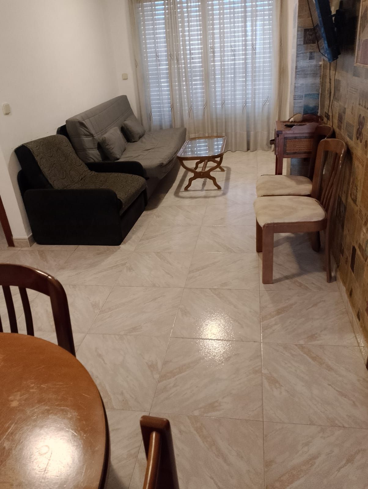 A living room with a sofa, a coffee table, and a dining table with chairs.
