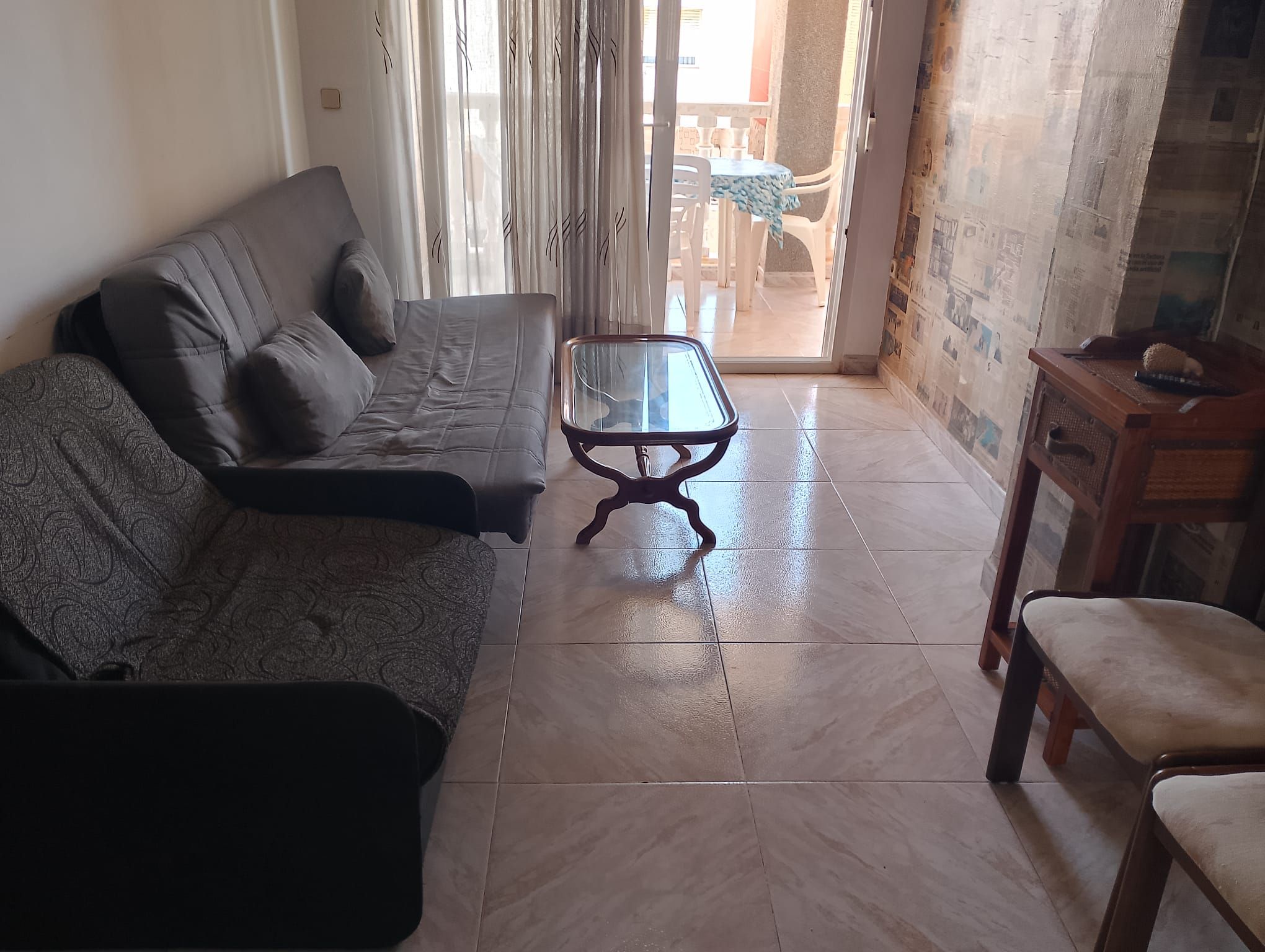 Ein Wohnzimmer mit einer Couch, einem Glastisch und einem Sessel.