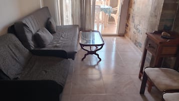 Ein Wohnzimmer mit einer Couch, einem Glastisch und einem Sessel.