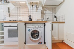 A compact kitchen with a built-in washing machine, a microwave, and a toaster.