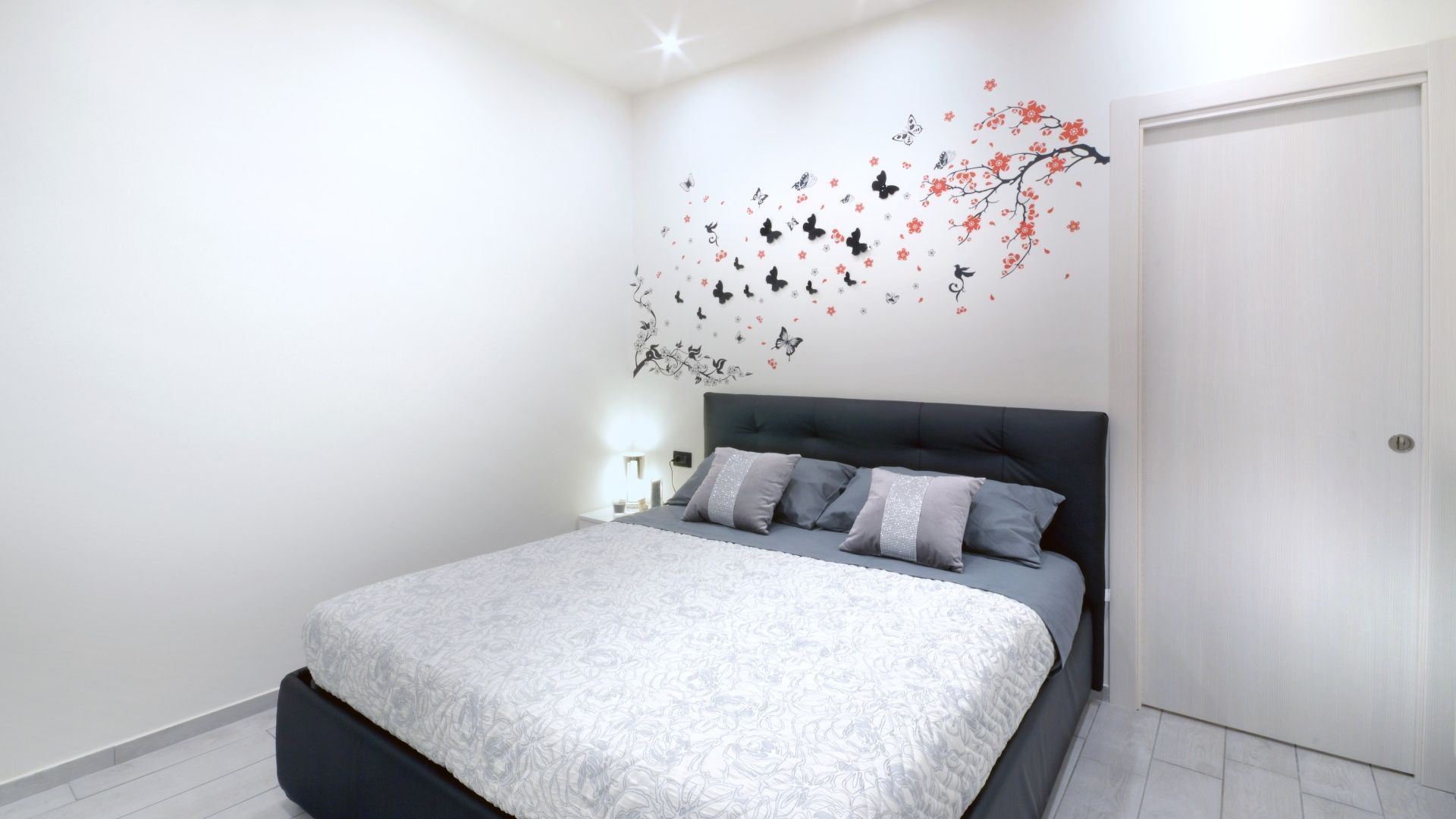 A bedroom with a bed, a nightstand, and a wall decoration.