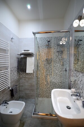 Un baño moderno con ducha de vidrio, dos lavamanos y un bidé.