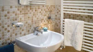 A bathroom with a white sink, a mirror, a towel rack, and a tiled wall. - HOME SWEET HOME (Napoli)