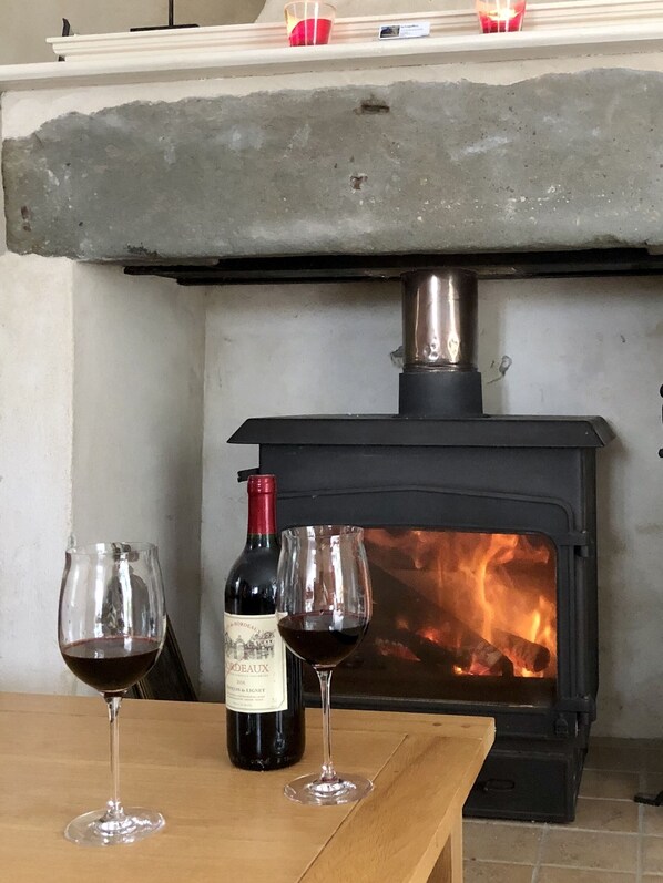 A fireplace with a bottle of wine and two glasses on a wooden table.