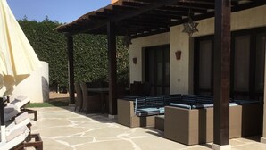 A covered outdoor patio with stone flooring, wicker furniture, and a pergola structure. - Extremely private villa with own pool (heating optional) - sleeps up to 6 (El Gouna)