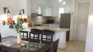 A dining area with a glass-top table, wooden chairs, and a vase with flowers. - Extremely private villa with own pool (heating optional) - sleeps up to 6 (El Gouna)