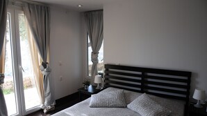 A bedroom with a bed, curtains, a nightstand, and a lamp. - Melolia A2 holiday home with pool and fabulous views (Alyki)