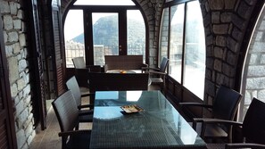 Enjoy meals in this cozy dining area with a glass-top table and wicker chairs, surrounded by a mountain view.