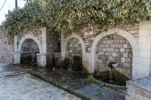 Stunning arched fountains set within a stone wall, surrounded by lush greenery and stone tiles.