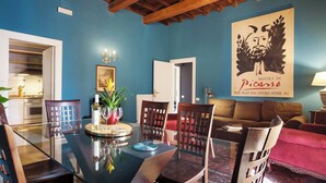 A dining area with a glass table, chairs, a red sofa, and a poster on the wall.