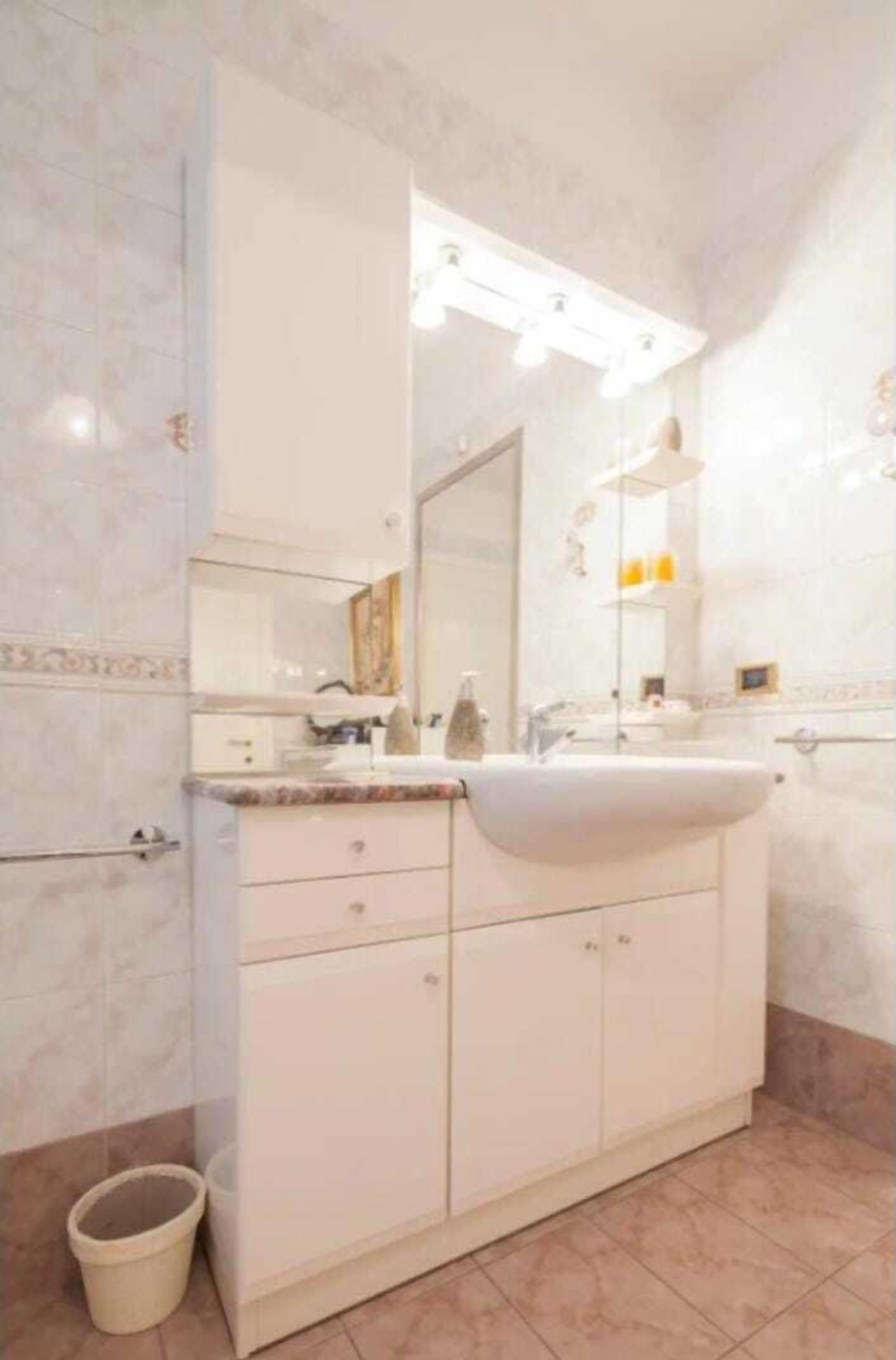 A bathroom with a large vanity, a mirror, and a light fixture above the sink.