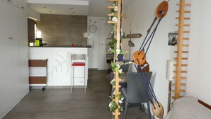 Una cocina moderna con una encimera blanca, una silla roja y un estante de madera con una guitarra.