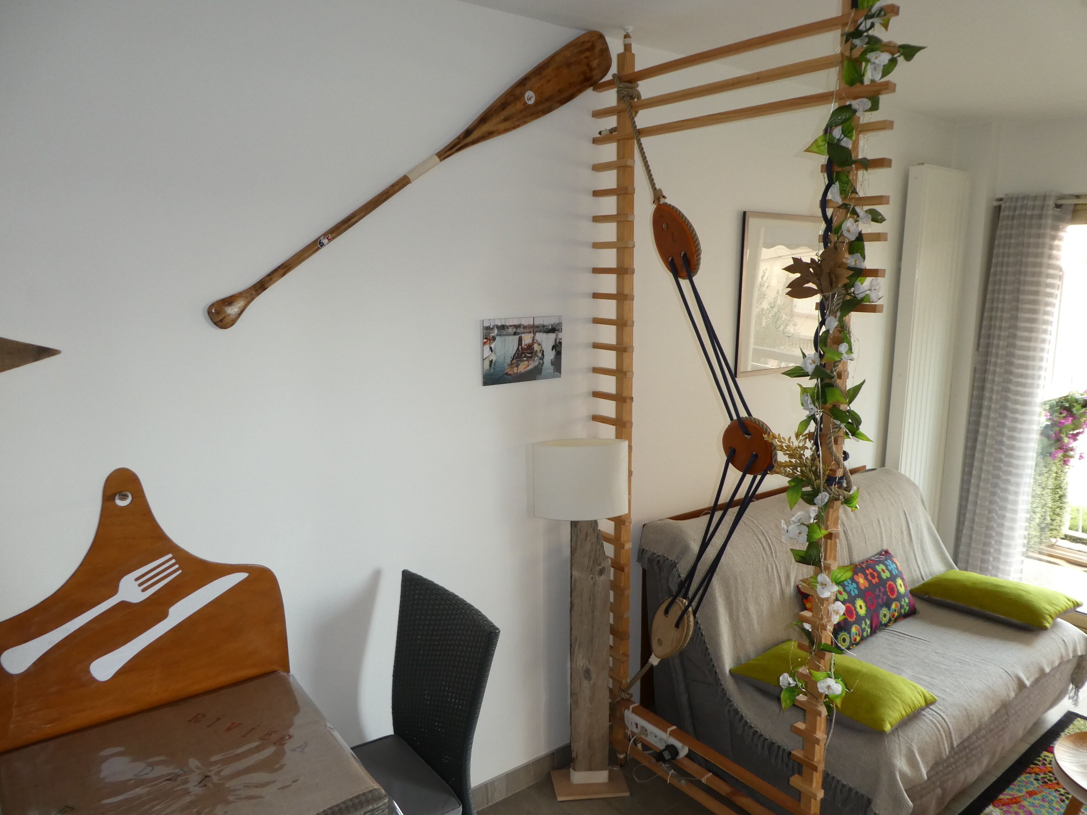Een knus slaapkamer met een bed, een houten trap, een wandlamp en een eettafel met bestekkunst.