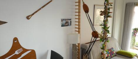 Een knus slaapkamer met een bed, een houten trap, een wandlamp en een eettafel met bestekkunst.