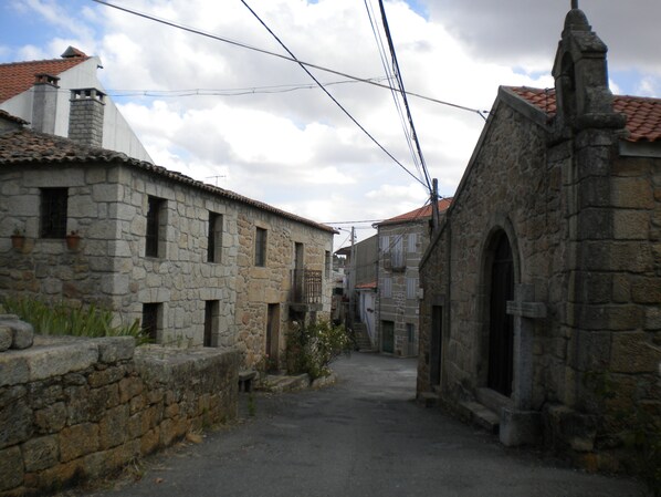 Eine enge Gasse mit Steinhäusern, einige mit sichtbaren Fenstern und Balkonen.