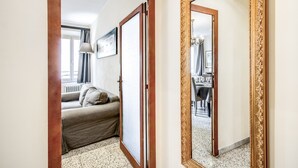 A hotel room with a bed, a sofa, a dining table with chairs, and a large mirror with an ornate frame. - Times Rome Colosseum, wide in wonderful location front Coliseum (Rome)
