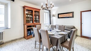 A dining area with a table set for six, surrounded by chairs, a wooden cabinet with glass doors, a chandelier, and a clock on the wall. - Times Rome Colosseum, wide in wonderful location front Coliseum (Rome)