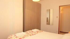 A hotel room with a bed, a wooden wardrobe, and a mirror on the wall. - Sea view, bright apartment in the center of Lido di Pomposa (Comacchio)