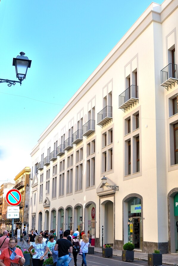 A building with multiple floors, balconies, and storefronts. - At the Corte Maqueda of Palermo historic center (Palermo)