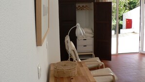 Una habitación con una mesa de madera, dos sillas, una lámpara de noche, un armario y vistas a través de un ventanal.