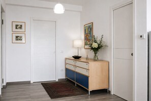 Un couloir avec une armoire en bois, une lampe et des tableaux encadrés accrochés au mur.
