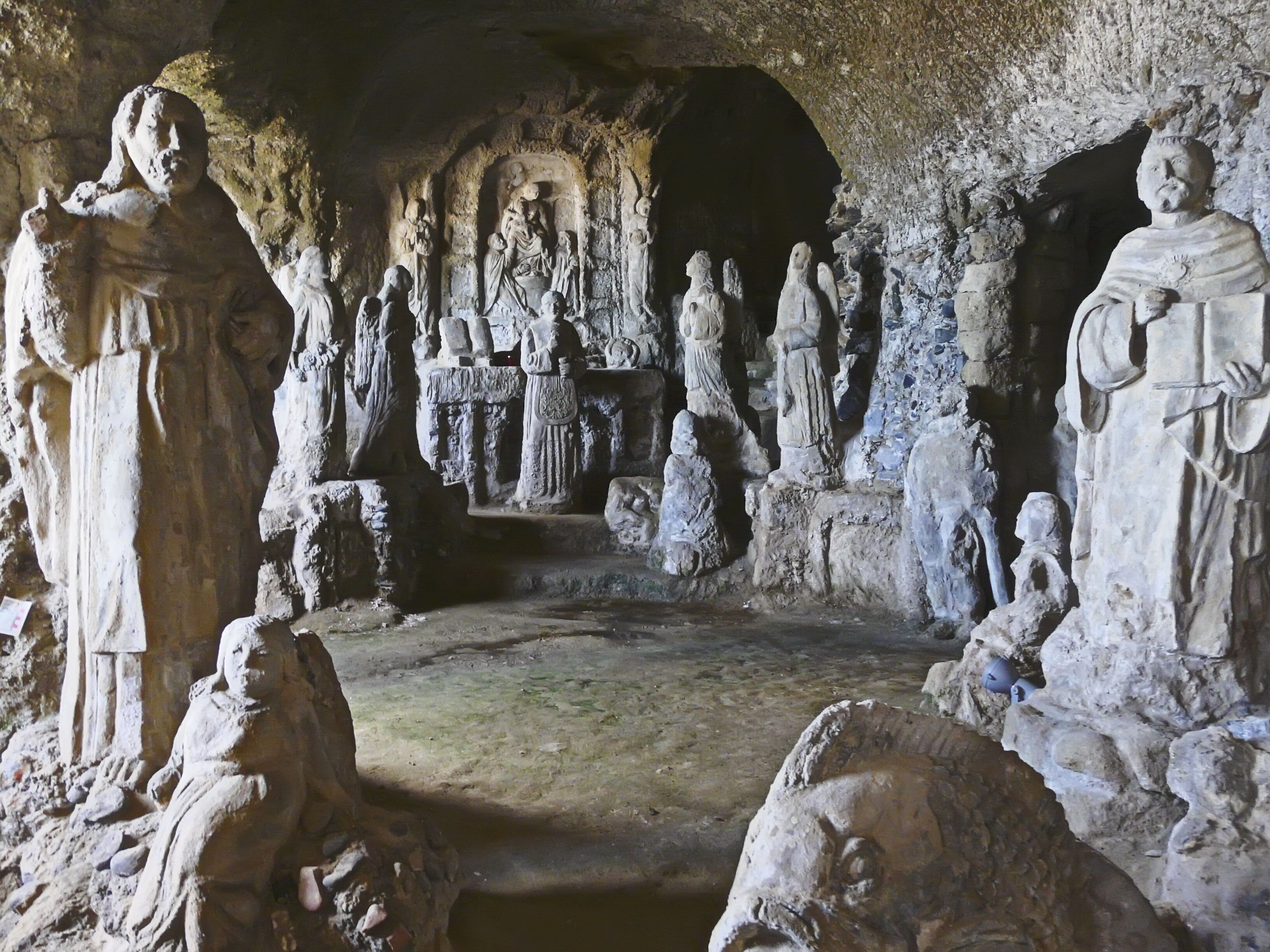 Una grotta con antiche incisioni e statue in pietra.