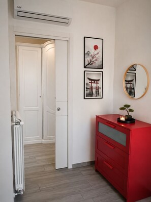 Une pièce avec un radiateur, une commode rouge et des œuvres d’art accrochées au mur.