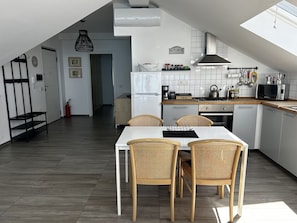 A modern kitchen with a dining table and chairs, a refrigerator, a stove, and a microwave.
