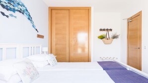 A bedroom with a bed, a wooden wardrobe, a wall-mounted plant, and a star-shaped light fixture.