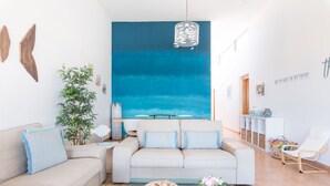 A modern living room with a large blue wall mural, a sofa set, a coffee table, and a side table with a vase.