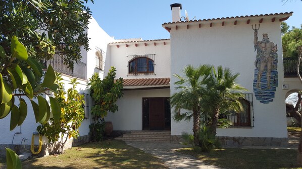 A white building with a tiled roof, a central entrance with a door, and a mural on the right side. - FABULOUS BEACHFRONT VILLA VERY CLOSE TO BARCELONA  (COMA RUGA)