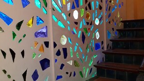 Eine Treppe mit Holzstufen und einer Wand, die mit bunten Mosaikfliesen verziert ist.