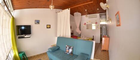 A living room with a blue sofa, a television, and a green stool.