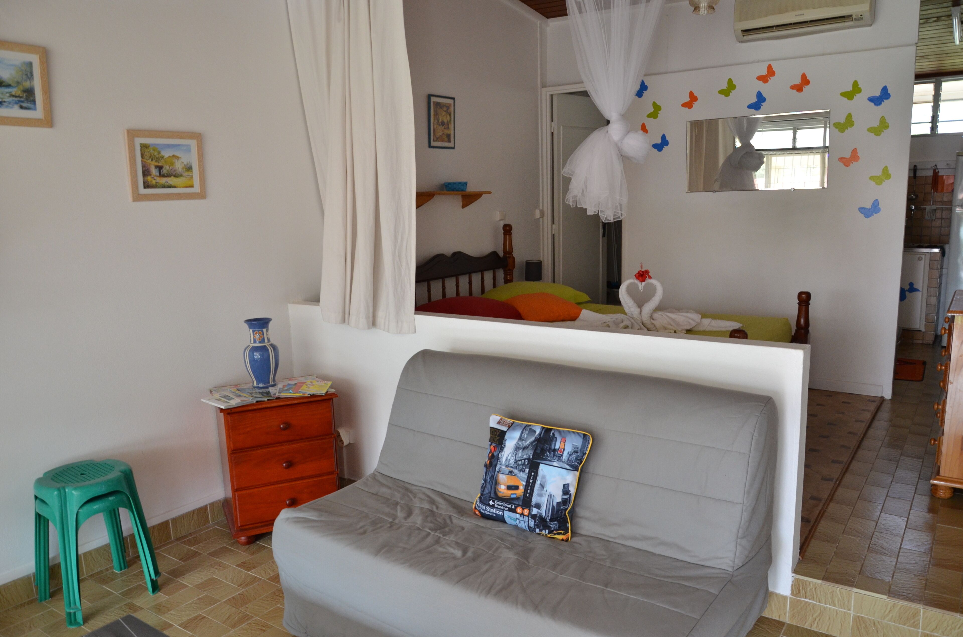 A bedroom with a bed, a dresser, a mirror, and a window with curtains.
