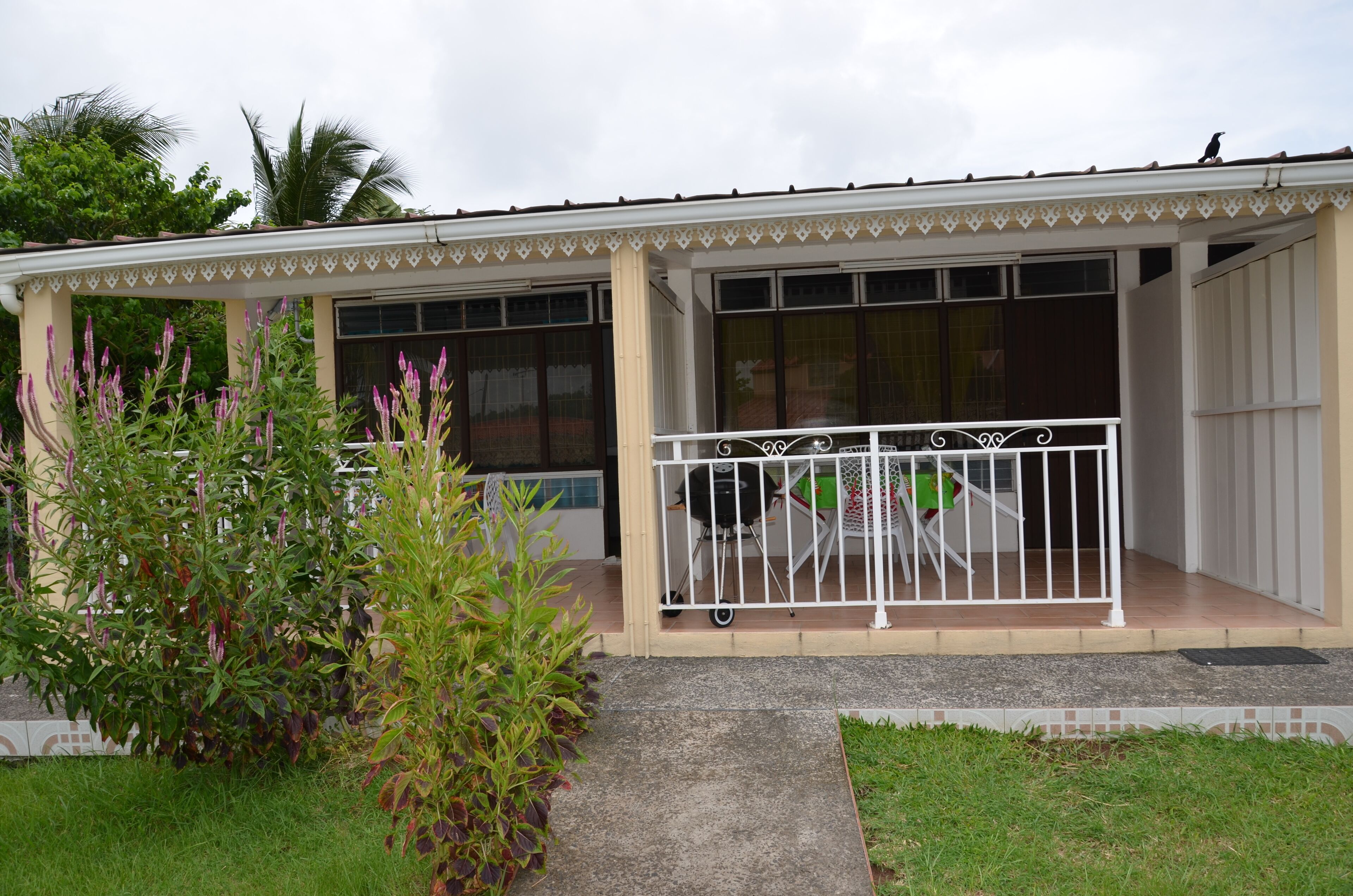 A single-story building with a covered porch, large windows, and a small fenced outdoor area.