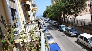 A narrow street lined with parked cars and buildings. - Family House (Cefalù)