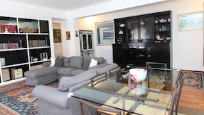 A living room with a sectional sofa, a glass-top dining table, and a black cabinet with shelves. - Family House (Cefalù)