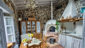 A rustic kitchen with a stone wall, wooden cabinets, and a brick oven.