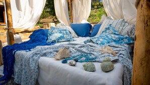 A bed with a canopy, blue and white patterned bedding, and seashells. - TERRE DI BEA COTTAGE BY THE SEA CEFALù ROMANTIC GATEAWAY PANORAMIC SEA VIEW (cefalu')