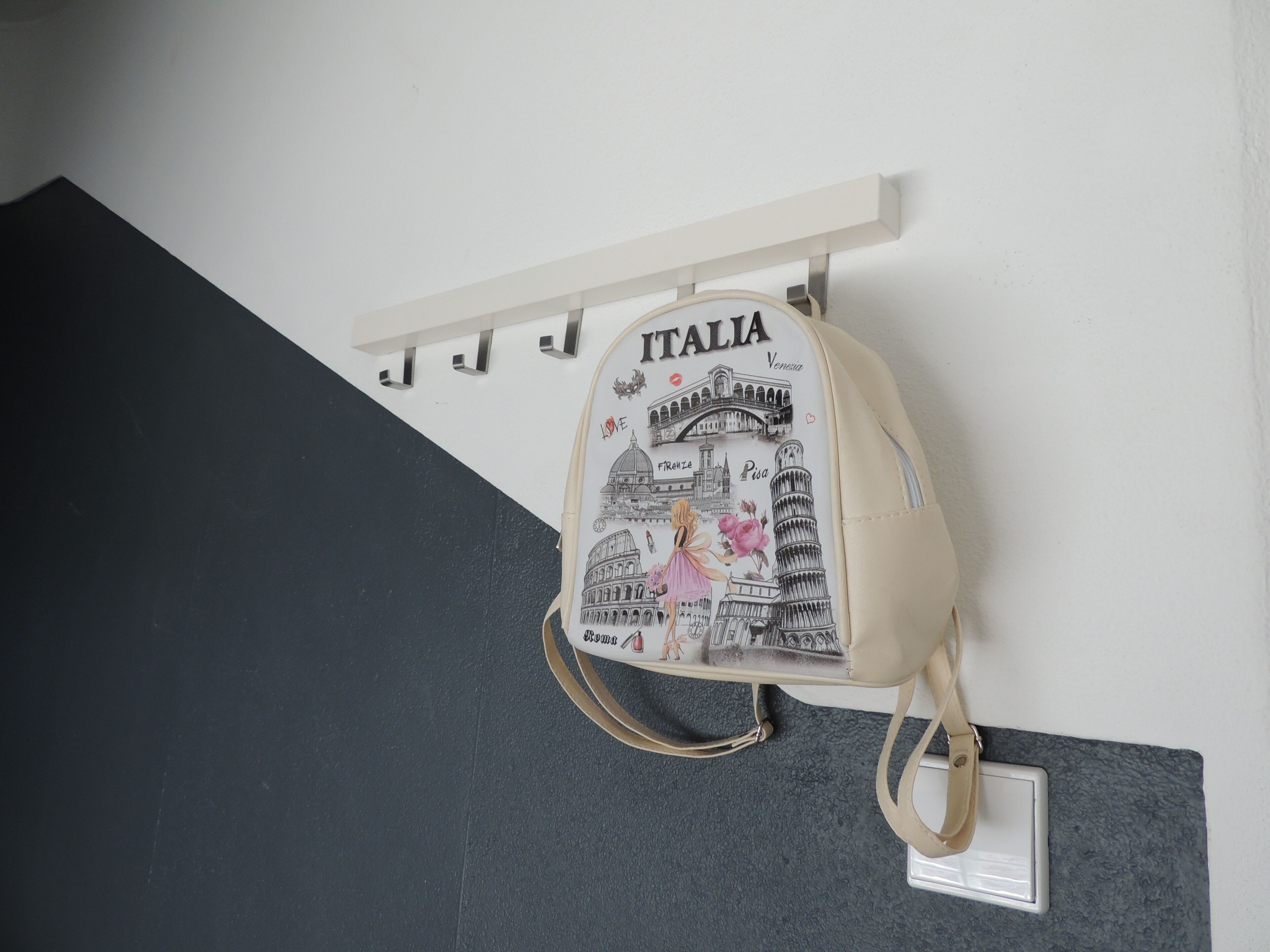 Un sac à dos orné d’un motif sur le thème de l’Italie, accroché à un mur.