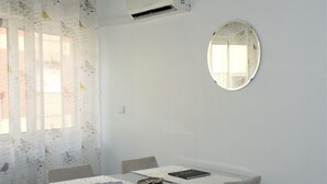 A dining area with a table, chairs, a round mirror, and an air conditioning unit. - RENDEZ VOUS PORTO I (T1) (Paranhos - Porto)