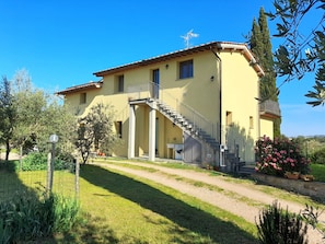 A two-story house with a balcony, a staircase, and a garden.