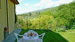 Mesa posta ao ar livre, com vista para uma paisagem verdejante e montanhas ao fundo.