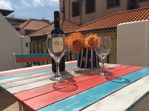 A table with a bottle of wine and two glasses on a colorful wooden table.
