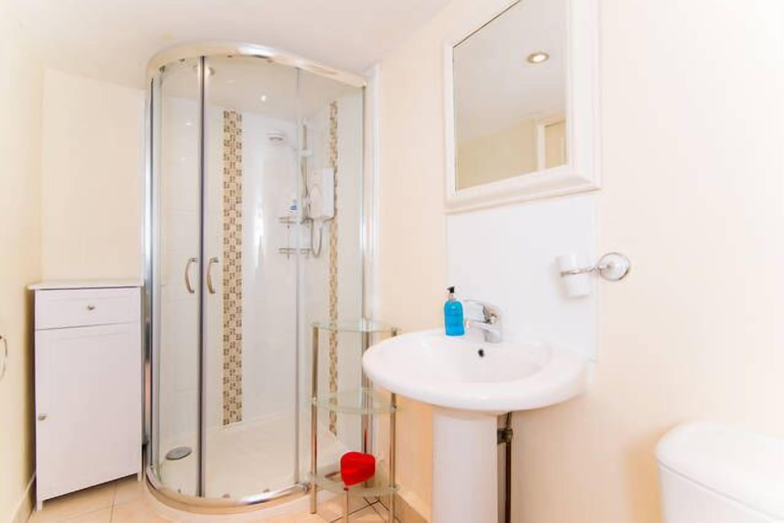 Ein modernes Badezimmer mit Duschkabine aus Glas, einem weißen Waschbecken und einer Toilette.